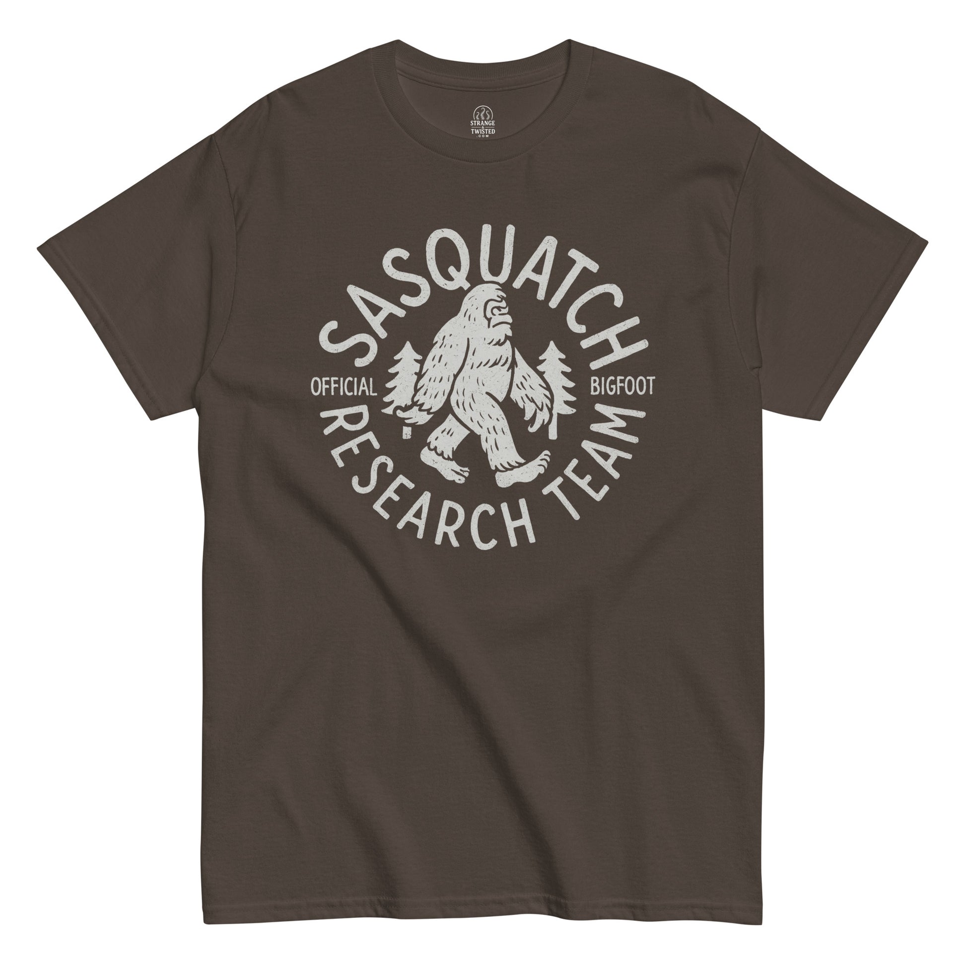 Sasquatch Research Team T-shirt showing white Bigfoot and pine trees design on dark brown background.