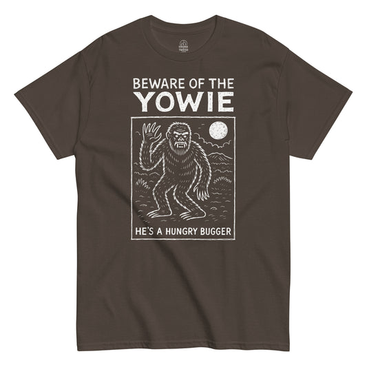 Beware of the Yowie T-shirt featuring white cryptid artwork and full moon design on brown fabric.
