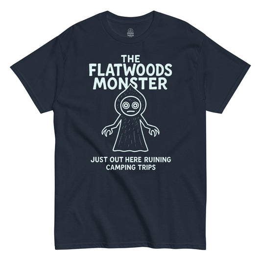 Navy Flatwoods Monster T-shirt with white cryptid illustration and text “Just Out Here Ruining Camping Trips,” paranormal humor apparel