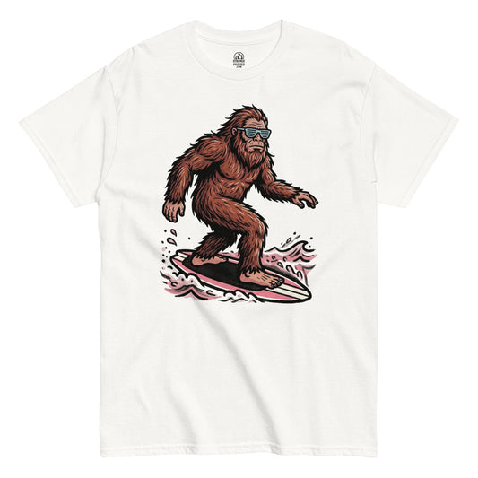 Surfing Bigfoot cryptid T shirt on white showing Sasquatch riding surfboard